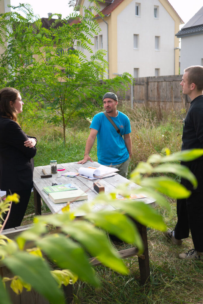 Junge Menschen stehen in einem Garten und sprechen miteinander